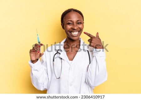 smiling confidently pointing to own broad smile, positive, relaxed, satisfied attitude. physician and syringe concept