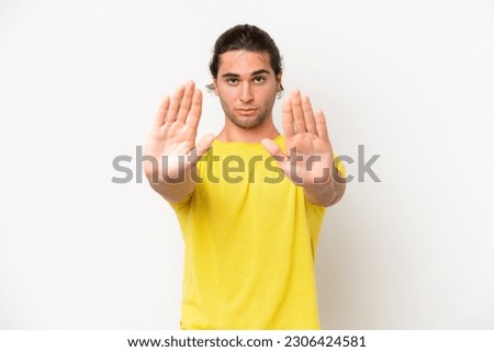Caucasian handsome man isolated on white background making stop gesture and disappointed