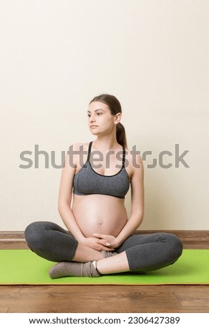 Pregnancy Yoga and Fitness concept at coronavirus time. Pregnant woman meditates indoor in yoga pose. Woman enjoying in meditation.
