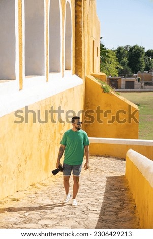 Young male tourist with camera entering the Convent of San Antonio in Izamal, Mexico.