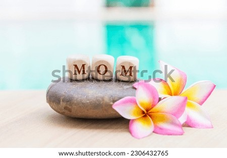 Mom on wooden cube with plumeria flower over blurred background, Mother's day card background idea