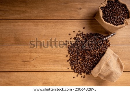 The picture of coffee beans stacked together on a wooden floor in a warm, light atmosphere, on a dark background, with copy space.