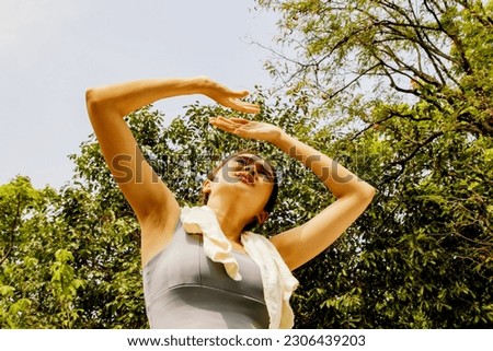 Asian woman doing sport jogging feeling sun and heat too hot during jogging in park sweltering summer weather covering face with hands covering face against UV rays : Sun protection health care concep Royalty-Free Stock Photo #2306439203