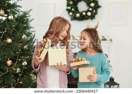 Cute little girls opening Christmas gifts at home