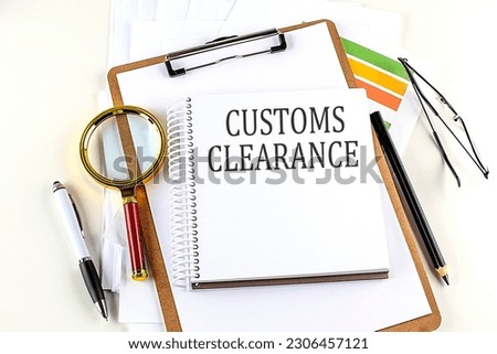 CUSTOMS CLEARANCE text on a notebook with clipboard on white background