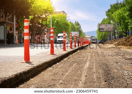 Restrictive plastic poles to control traffic on the road during repair work. Against the background of passing cars. 