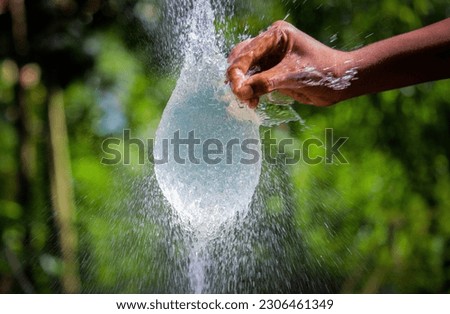 Water splash in slow motion from a balloon with hand punch Royalty-Free Stock Photo #2306461349