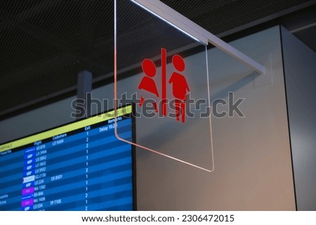 Red public toilet sign on transparent glass hanging indoors