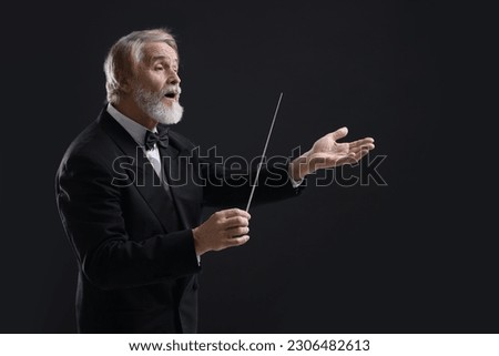 Professional conductor with baton on black background Royalty-Free Stock Photo #2306482613