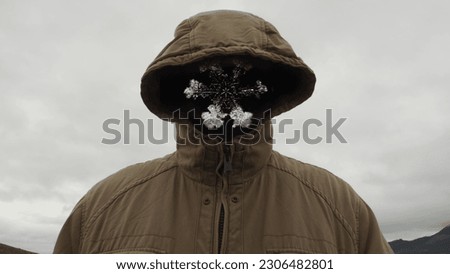 A snowflake instead of the face of a man in a hood against a cloudy sky. Computer graphics. Royalty-Free Stock Photo #2306482801