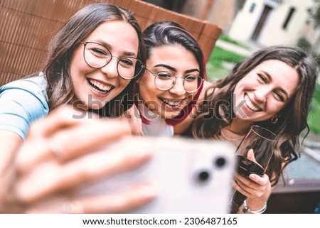 group of happy friends taking selfie with mobile phone outdoors at winery bar-Three young girls having fun drinking red wine at restaurant table-Life style concept with multiracial female 
