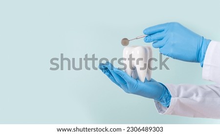 Dental clinic special offer banner. Dentist hands hold a healthy white tooth model and dentist mirror on a blue background. Copy space. Teeth care, dental treatment, tooth extraction, implant concept. Royalty-Free Stock Photo #2306489303