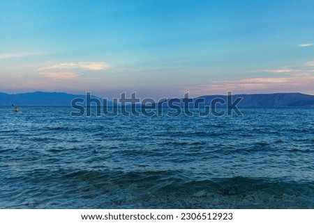 Calm seascape. Blue sea under clear sky. Mountains on horizon. Sea waves. Positive screensaver.
