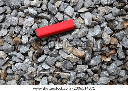 A discarded single use red vape has been thrown away left on some grey gravel. Royalty-Free Stock Photo #2306514871