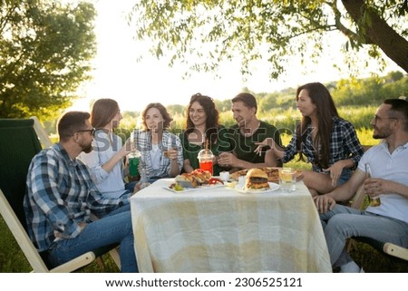 Group of young happy friends having pic-nic outdoors - People having fun eating pizza and celebrating while grilling ata barbacue party in a countryside