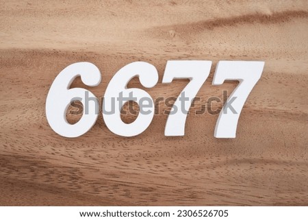 White number 6677 on a brown and light brown wooden background.