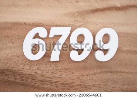 White number 6799 on a brown and light brown wooden background.