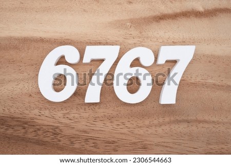 White number 6767 on a brown and light brown wooden background.