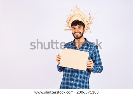 Happy smiling man in festa junina outfit displaying blank white sign on white studio background, mockup for logo or design. Boy in costume for June party with empty advertising banner, copy space