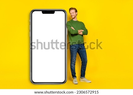 Full length photo of cute dreamy man wear pullover arms crossed looking gadget empty space isolated yellow color background