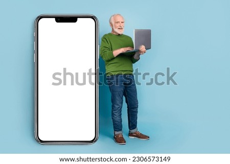 Full length photo of cheerful grandparent hold netbook stand near huge phone screen isolated on blue color background