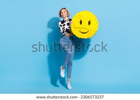 Full size photo of excited charming girl jumping hands hold large smiley emoji collage isolated on blue color background