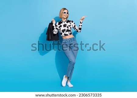 Full body portrait of gorgeous positive lady hold boutique bags direct finger empty space isolated on blue color background