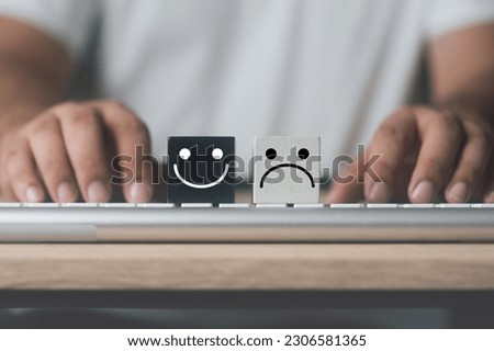 Wood block face sad and wood block smiles on keyboard for evaluation. Customer satisfaction or emotional evaluation concept. Positive and negative emotions. Mental health, wellness and healthy concept