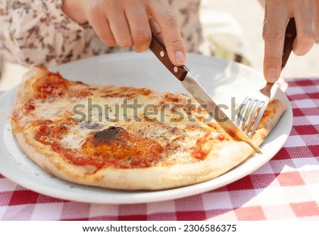 Cutting pizza into pieces. Woman cuts pizza close-up. 