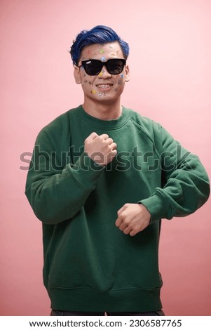 Joyful young man with stickers on face and sunglasses dancing