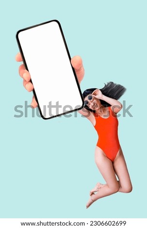 Top view full size woman of Asian ethnicity in red swimsuit showing empty smart phone screen isolated on blue background. Summer vacation sea rest sun tan concept. Royalty-Free Stock Photo #2306602699