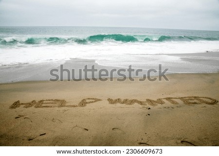 Help Wanted. Words written in beach sand. The words Help Wanted written in the sand on the beach with the ocean as the background. Everyone Loves the beach. Companies are always looking for help.