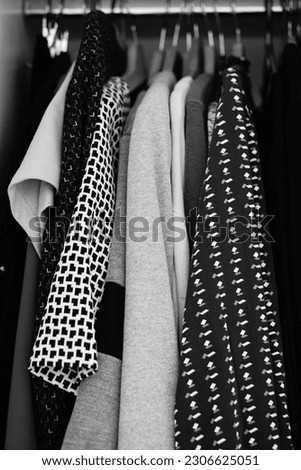 A vertical grayscale closeup of the clothes in a wardrobe. Royalty-Free Stock Photo #2306625051