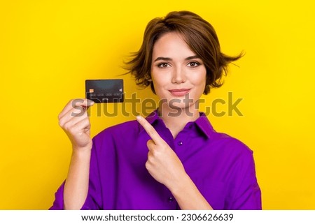Portrait photo of young serious banker woman wear purple shirt demonstrate new atm card receive money isolated on yellow color background