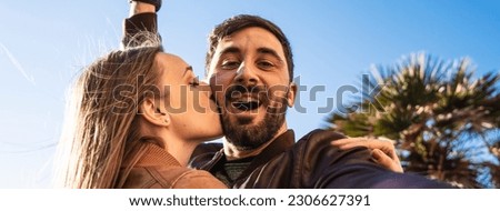 Horizontal banner or header with hipster young couple having fun taking a selfie portrait against a beautiful panorama at sunset. Boyfriend and girlfriend in love smiling at the camera together.