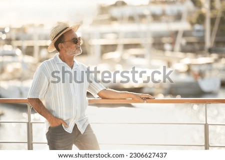 Enjoy Golden Vacation. Happy European Senior Man Looking Aside At Docked Yachts In Marina Port, Standing At Pier Wearing Summer Hat And Sunglasses. Gentleman Planning Sea Adventure. Free Space Royalty-Free Stock Photo #2306627437