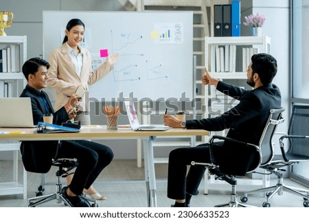 Asian manager point to project on board that present by pretty business woman in meeting room of office with day light. 