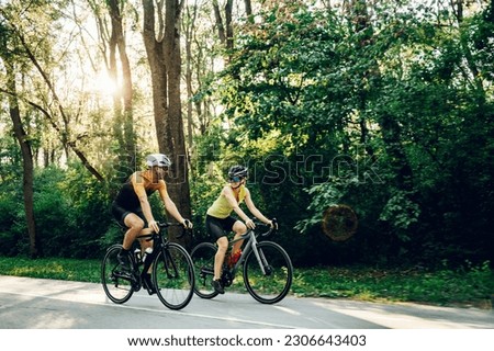 Sporty young woman and man on bicycles during weekend cycle ride outside of the city. Wearing sports clothes and helmets. Traveling by high-performance sport bicycles. Sports lifestyle. Copy space. Royalty-Free Stock Photo #2306643403