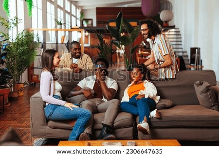 Diverse group of a five young relaxed people having a conversation while sitting on the couch in the living room Royalty-Free Stock Photo #2306647635