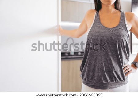 unrecognizable woman in sportswear doing pectoral stretch with arm supported at home. copy space. Royalty-Free Stock Photo #2306663863