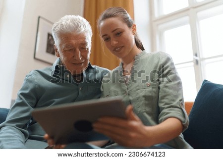 Senior man with his granddaughter using digital tablet. Royalty-Free Stock Photo #2306674123