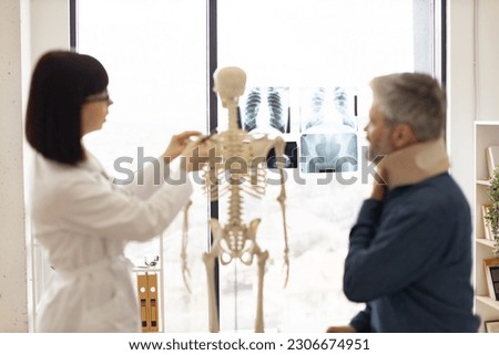 Focus on detailed x-ray pictures of human chest and pelvic bones placed on window panel with adult people talking on blur foreground. Medical imaging test creating radiographs for initial diagnosis.