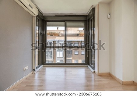 An empty window front living room with air conditioning, wooden floor and dark aluminum windows