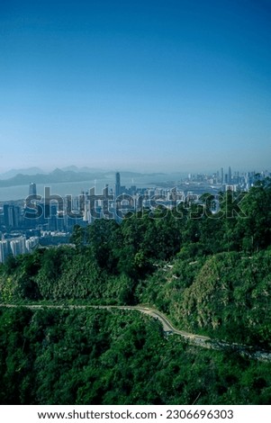 A vertical shot of the Victoria Peak with the view of Hong Kong in the background under a blue sky.