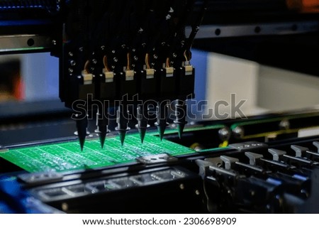 Automatic SMD pick and place machine during work - assembly of computer circuit board at factory - close up. Automated technology, industrial, robotic, electronic, production, manufacturing concept Royalty-Free Stock Photo #2306698909