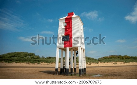 Red and white lighthouse on the beach.