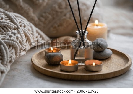 Apartment natural aroma diffusor with sea breeze fragrance. Burning candles on bamboo tray, cozy home atmosphere. Relaxation, detention zone in the living or bedroom. Stones as decor Royalty-Free Stock Photo #2306710925