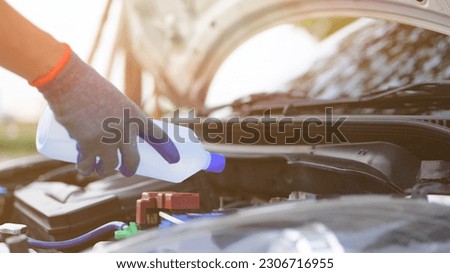 Man holding distilled or deionized water to refill car battery. Car inspection and maintenance concept. Royalty-Free Stock Photo #2306716955
