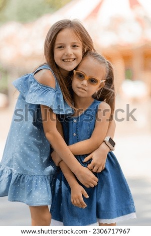 two little girls are happily walking in the amusement park in the summer. International Children's Day. A child with down syndrome. High quality photo