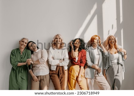 Multi-ethnic group of relaxed mature women bonding and smiling while leaning on the wall Royalty-Free Stock Photo #2306718949